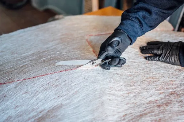 Fiberglass mat; worker cutting fiberglass.